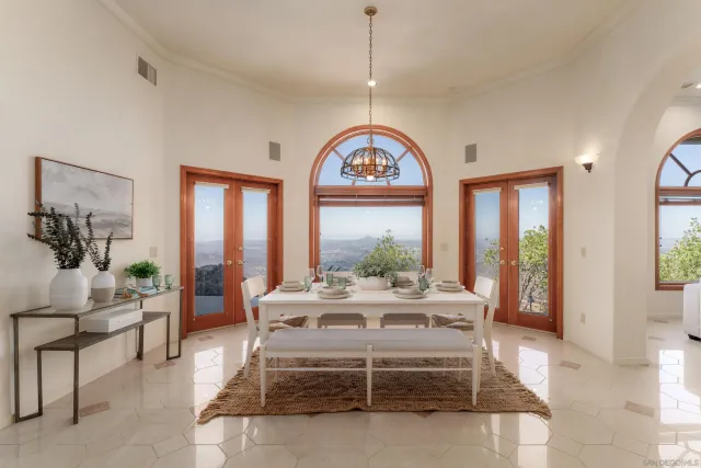 a view of a dining room with furniture large windows and a chandelier