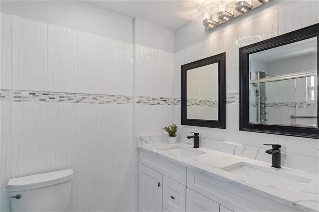 307 161st Avenue Redington Beach, FL 33708 - Photo 23 of 41 a bathroom with a double vanity sink toilet and mirror
