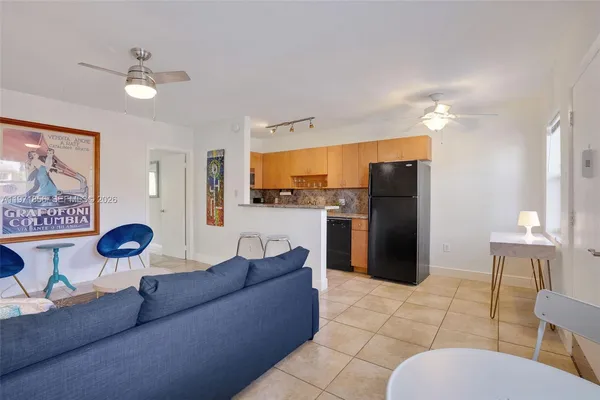 a living room with stainless steel appliances furniture a rug and a kitchen view