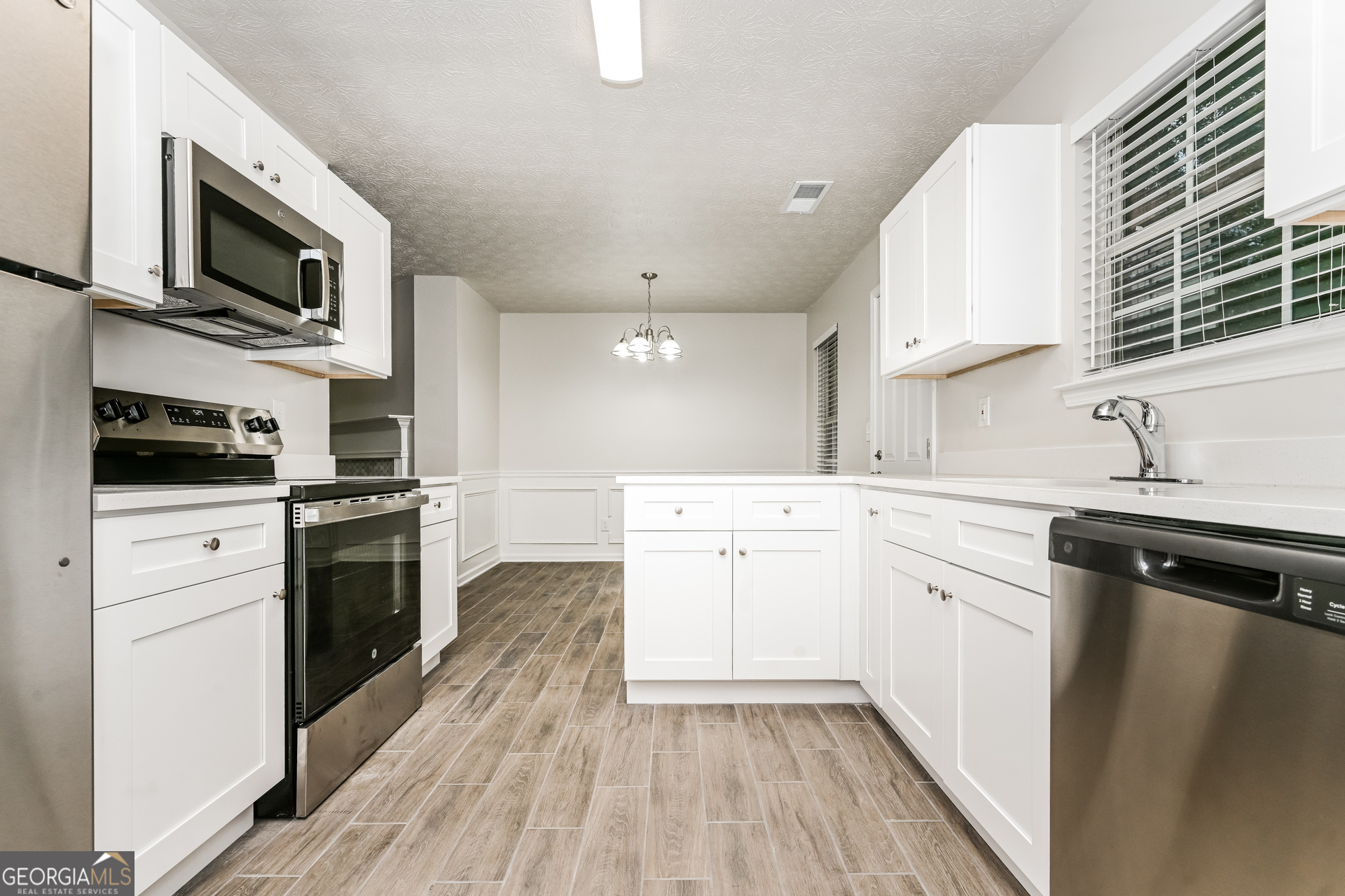 4392 Chester Lane Ellenwood, GA 30294 - Photo 7 of 17 a kitchen with a sink wooden floor and stainless steel appliances