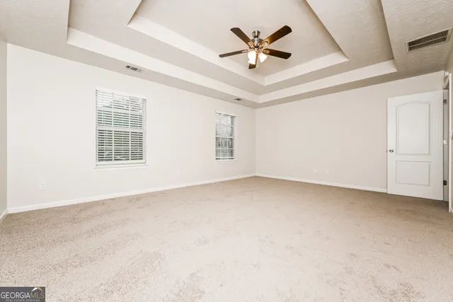 an empty room with windows and fan