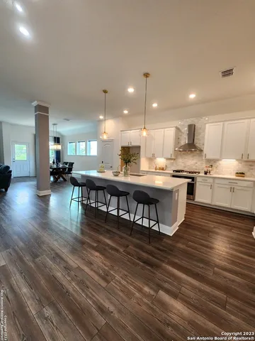 a kitchen with stainless steel appliances granite countertop a stove top oven a dining table and chairs with wooden floor