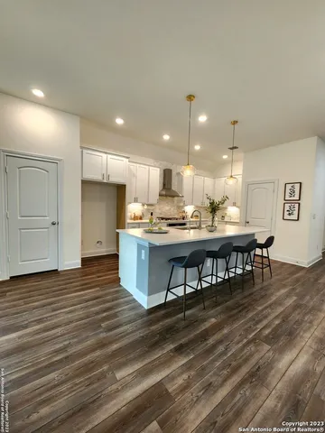 a open kitchen with kitchen island a sink dishwasher and a refrigerator with wooden floor