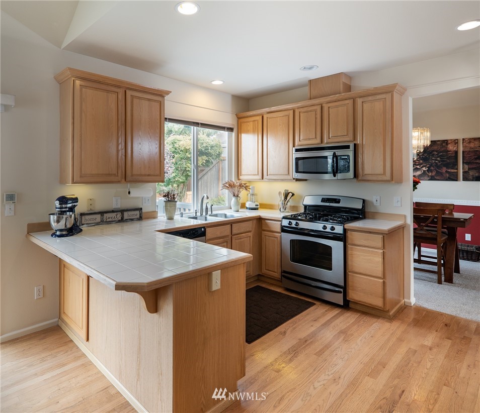 2825 202nd Street Southeast Bothell, WA 98012 - Photo 8 of 24 a kitchen with kitchen island granite countertop a stove top oven a sink and cabinets
