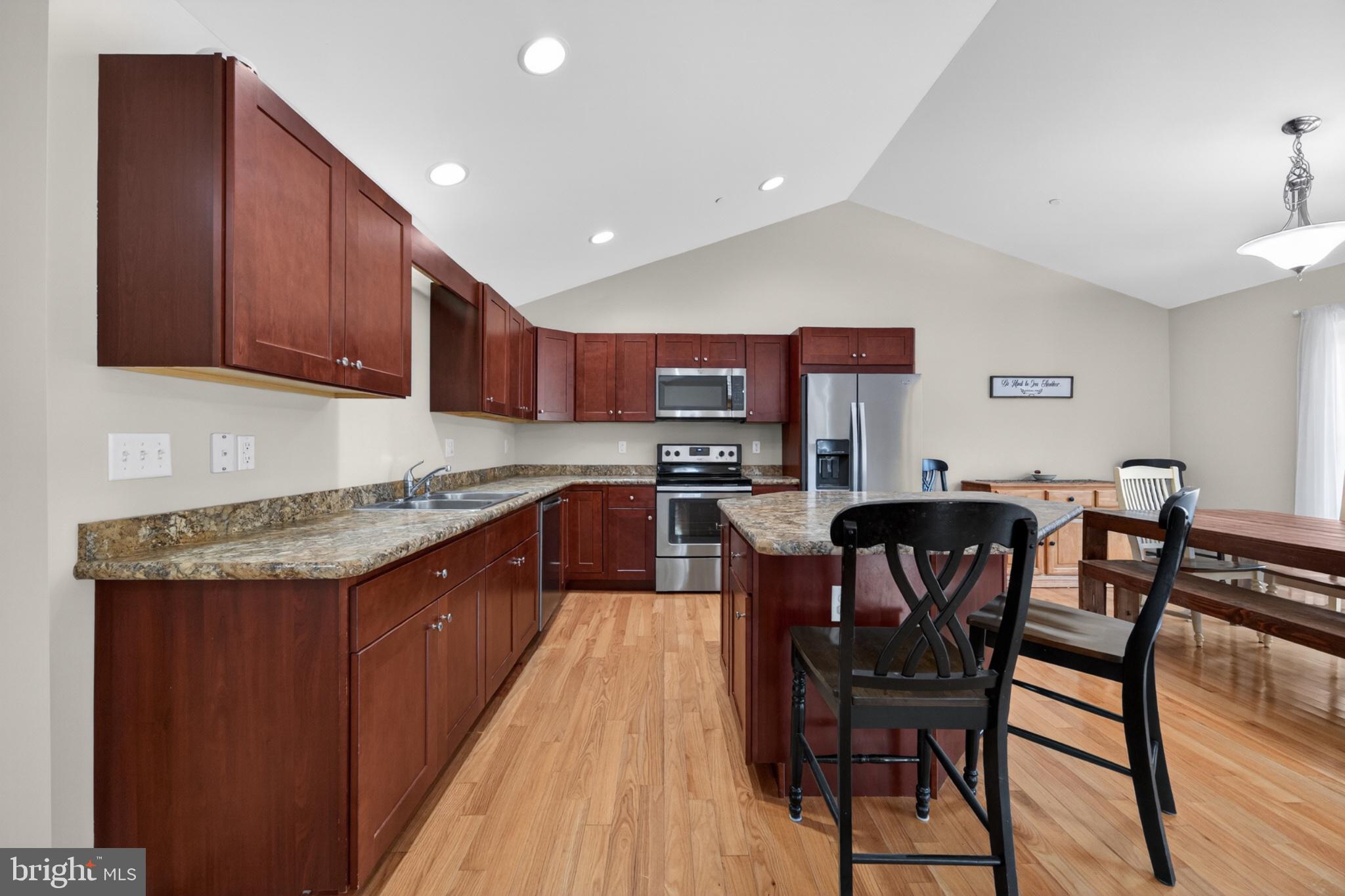 23283 Magnolia Hills Road Denton, MD 21629 - Photo 11 of 54 a kitchen with stainless steel appliances granite countertop wooden cabinets a dining table and chairs