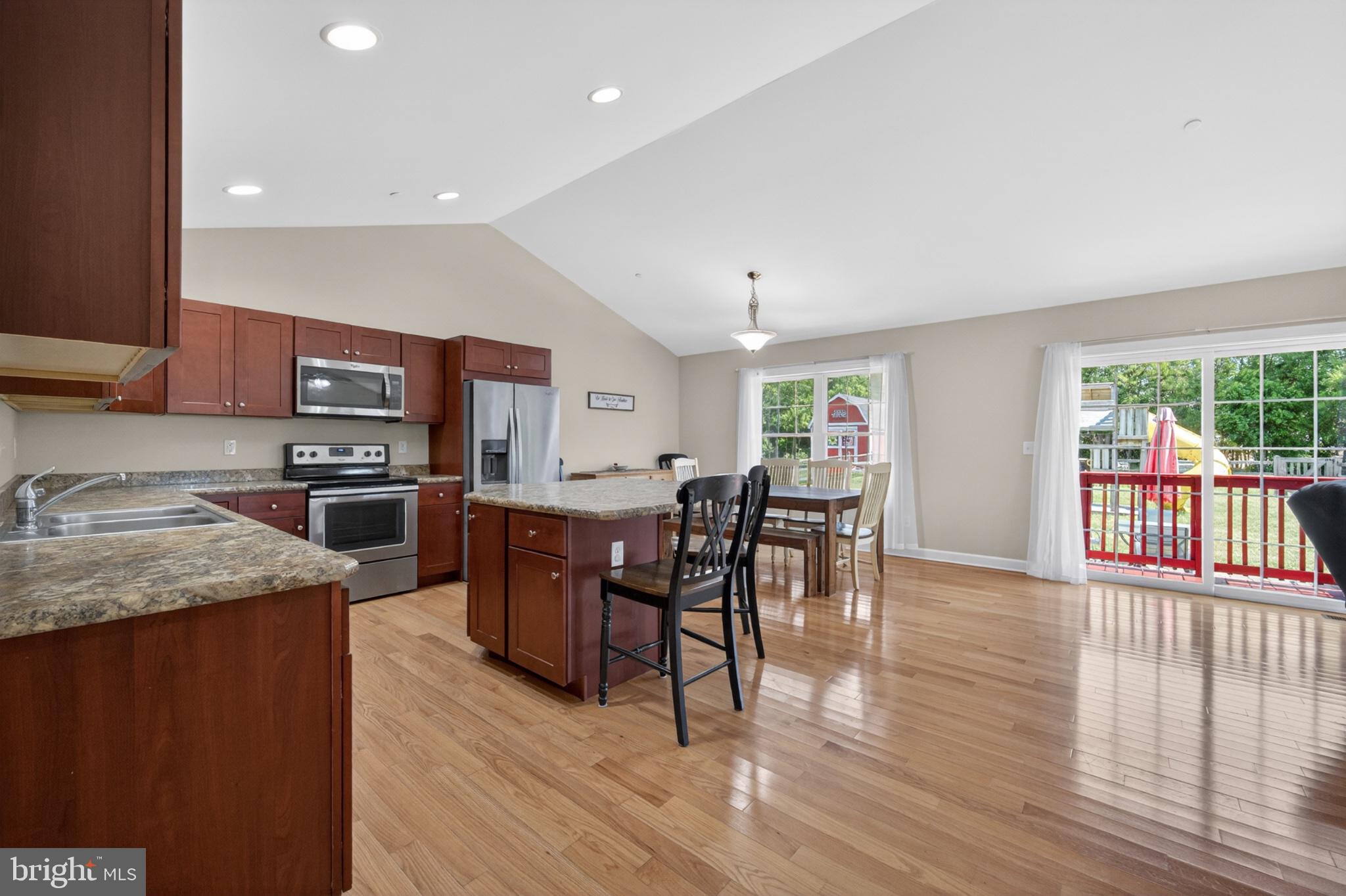 23283 Magnolia Hills Road Denton, MD 21629 - Photo 14 of 54 a kitchen with stainless steel appliances granite countertop a stove top oven a sink dishwasher a dining table and chairs with wooden floor