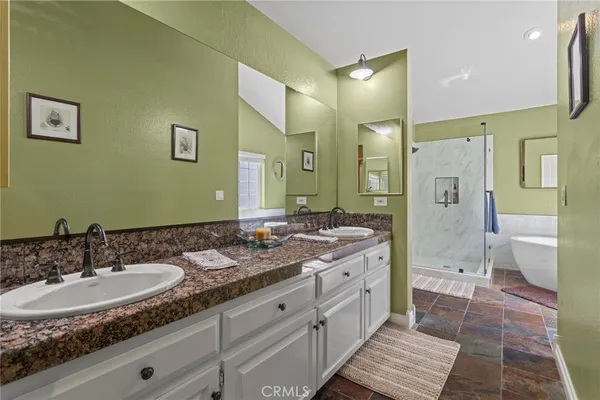 a bathroom with a granite countertop double vanity sink mirror and shower