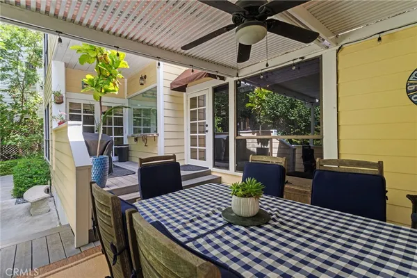 a view of a patio with couches chairs potted plants and floor to ceiling window with wooden floor