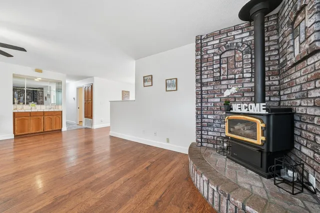 a view of an empty room with wooden floor and a fireplace