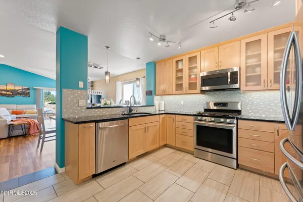 a kitchen with stainless steel appliances granite countertop a stove a sink and a microwave