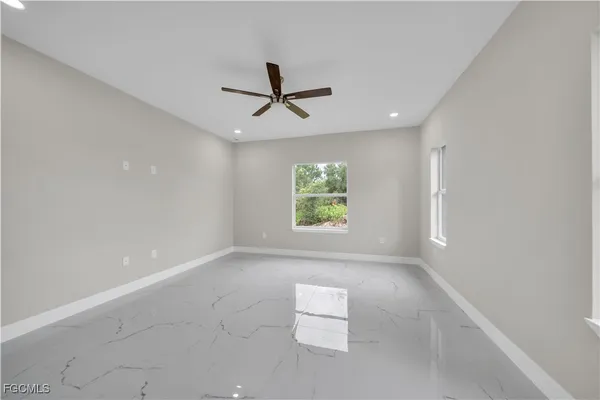 an empty room with windows and ceiling fan
