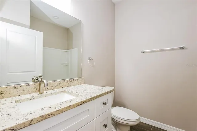 a bathroom with a granite countertop sink a toilet and a mirror
