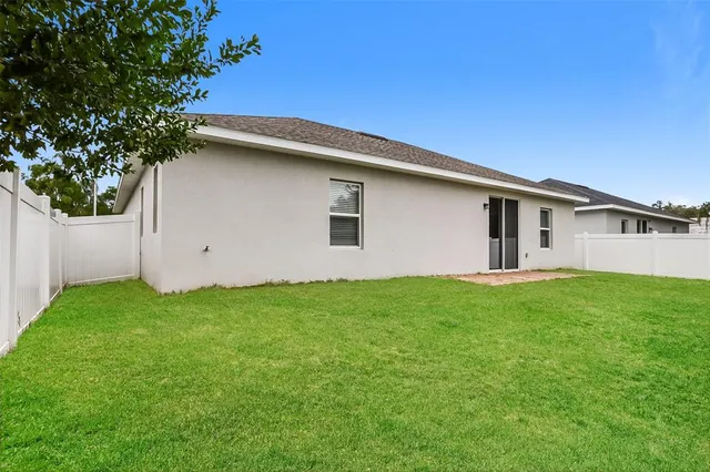 a backyard of a house with lots of plants and large tree