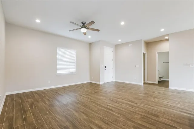 a view of an empty room with wooden floor and a window