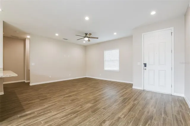 a view of an empty room with wooden floor and a window
