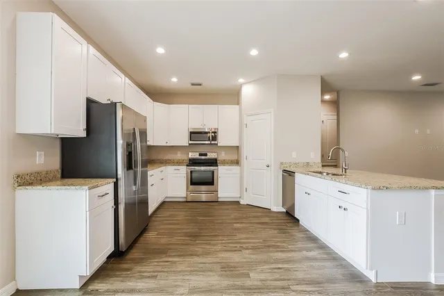 a large kitchen with stainless steel appliances kitchen island a sink a stove and a refrigerator