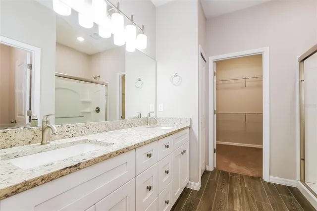 a bathroom with a granite countertop double vanity sink and mirror