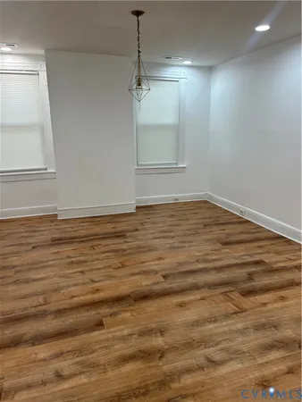 a view of an empty room with window and wooden floor