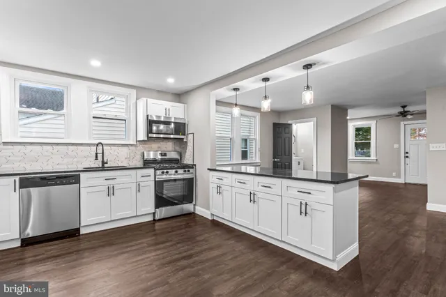 a large kitchen with granite countertop a stove top oven a sink a dishwasher and wooden cabinets