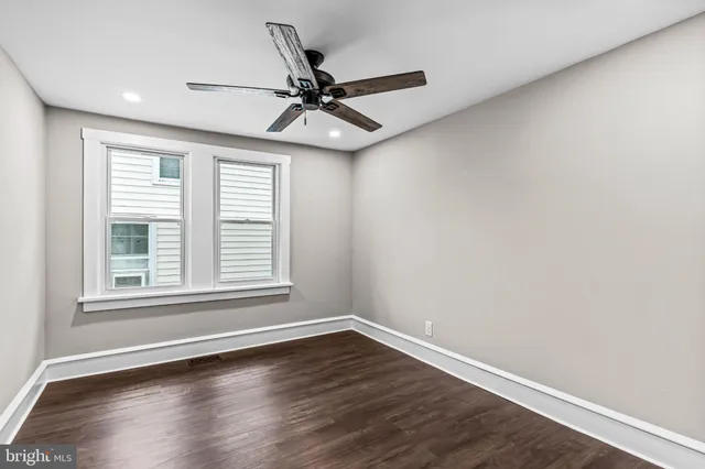 an empty room with wooden floor fan and windows