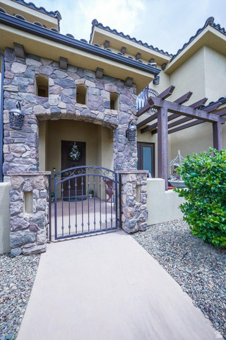 3683 South 2640 West St. George, UT 84790 - Photo 9 of 41 Stone facade entry with arched portico, wrought iron gate, and decorative exterior lighting fixtures