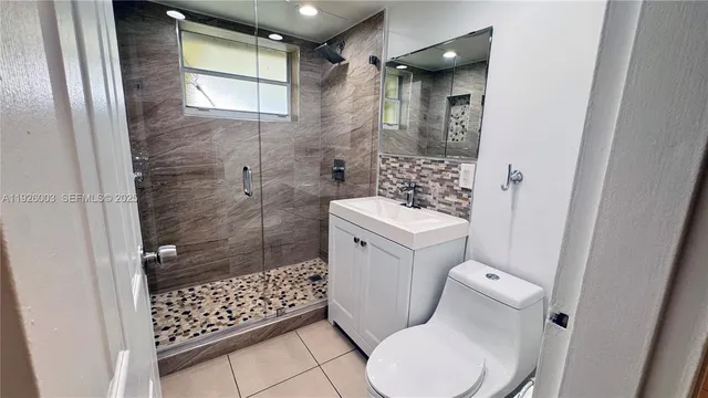 a bathroom with a toilet a sink a shower and a window