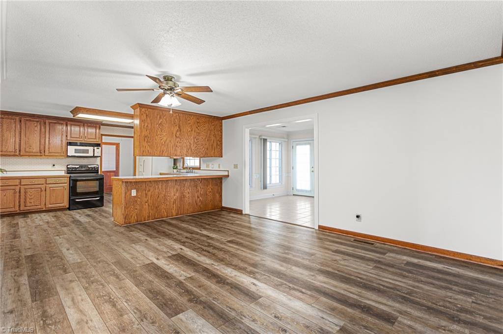 7021 Eaglesfield Road Gibsonville, NC 27249 - Photo 49 of 49 This space features an open floor plan connecting the kitchen and den, with fresh paint and updated vinyl plank flooring.