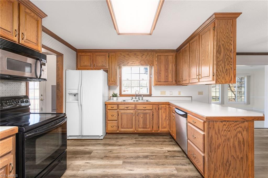 7021 Eaglesfield Road Gibsonville, NC 27249 - Photo 17 of 49 All appliances stay for your cooking pleasure, including a slide-in range, attached microwave, stainless steel dishwasher, and white side-by-side refrigerator.