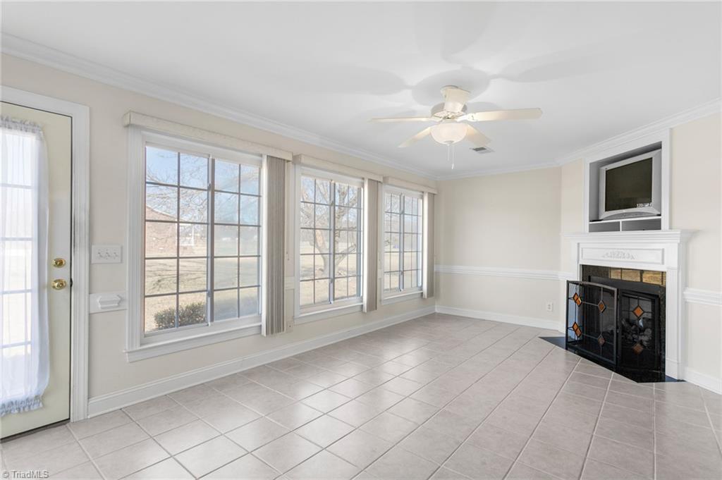 7021 Eaglesfield Road Gibsonville, NC 27249 - Photo 23 of 49 Enjoy time in the sunroom, conveniently connected to the den. This 12 x 20 tiled sunroom features sliding windows on all sides, a fireplace with gas logs, and a TV niche.