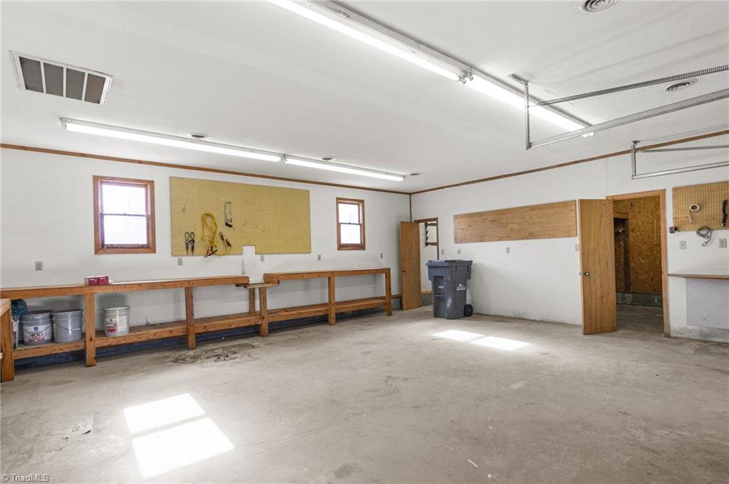 7021 Eaglesfield Road Gibsonville, NC 27249 - Photo 42 of 49 An additional room located behind the main garage area, featuring built-in workbenches and storage for tools and equipment.