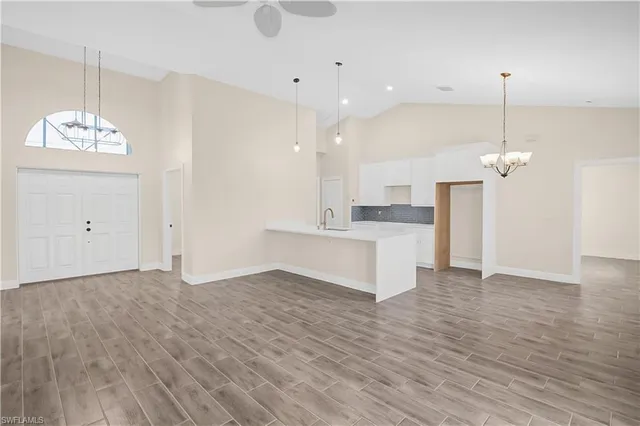 a view of a kitchen with granite countertop a sink dishwasher a refrigerator and a fireplace with wooden floor