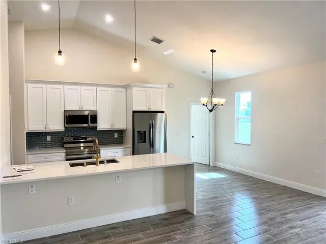 a kitchen with kitchen island a refrigerator and a stove top oven