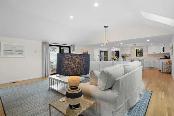 a living room with furniture kitchen view and a chandelier