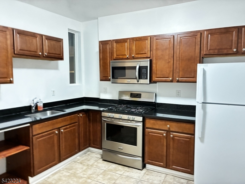 73 Wolcott Terrace Newark, NJ 07112 - Photo 20 of 20 a kitchen with granite countertop wooden cabinets and stainless steel appliances