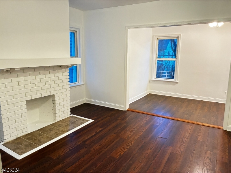 73 Wolcott Terrace Newark, NJ 07112 - Photo 4 of 20 an empty room with wooden floor a fireplace and windows