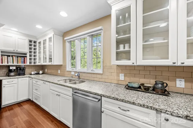 a kitchen with granite countertop stainless steel appliances a sink window and cabinets