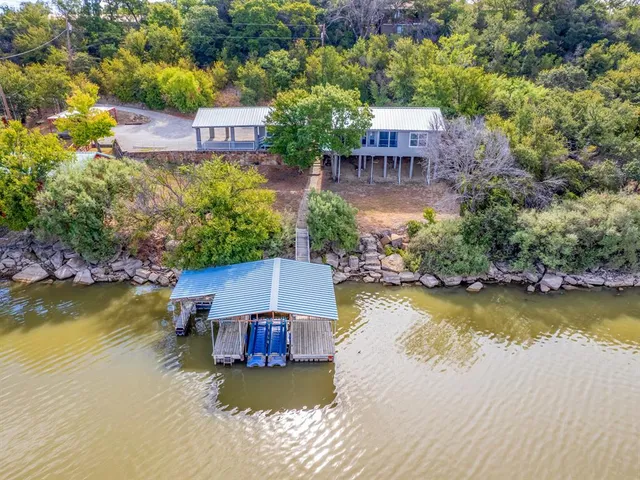 an aerial view of a house with swimming pool a yard and a patio