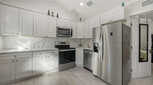 a kitchen with white cabinets and stainless steel appliances