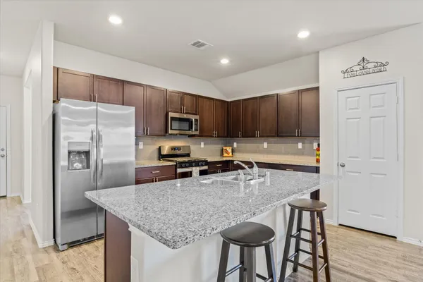 a kitchen with refrigerator a sink and chairs