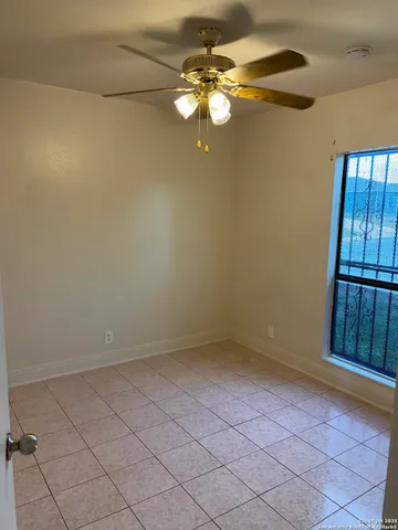 a view of an empty room with a chandelier fan
