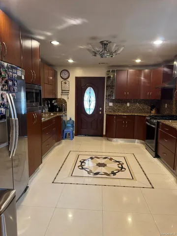 a kitchen with stainless steel appliances granite countertop a refrigerator a stove a sink and a microwave