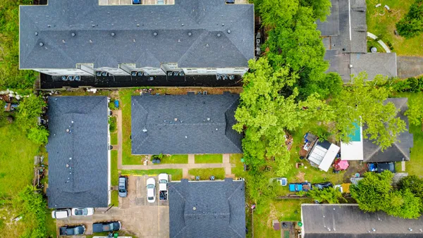 an aerial view of residential houses with outdoor space and trees