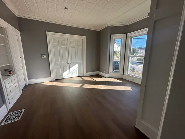 a view of an empty room with window and wooden floor