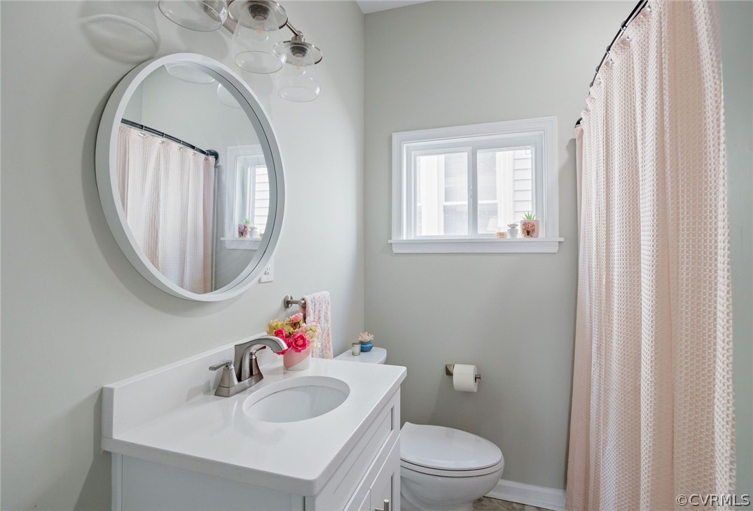 2900 Decatur Street Richmond, VA 23224 - Photo 27 of 35 a bathroom with a toilet a sink a mirror and a window