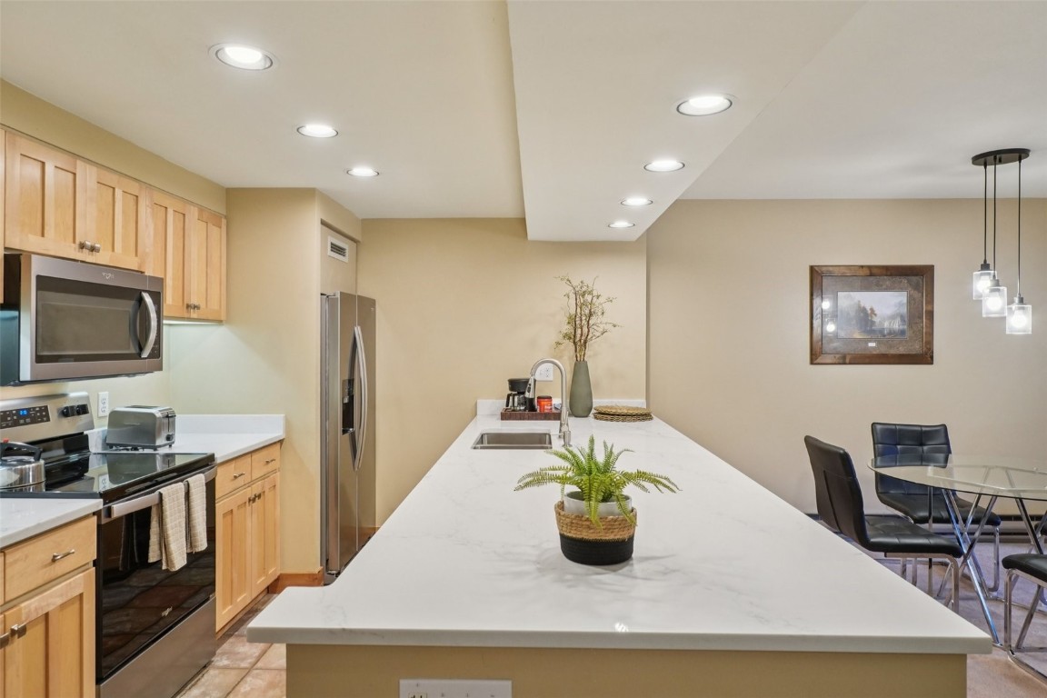 22097 Saints John Road, Unit 2506 Keystone, CO 80435 - Photo 11 of 47 Kitchen with appliances with stainless steel finishes, recessed lighting, light stone countertops, and a peninsula