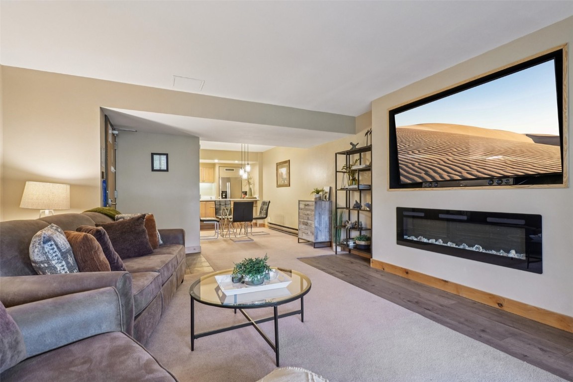 22097 Saints John Road, Unit 2506 Keystone, CO 80435 - Photo 3 of 47 Living room with a glass covered fireplace, wood finished floors, and a baseboard heating unit