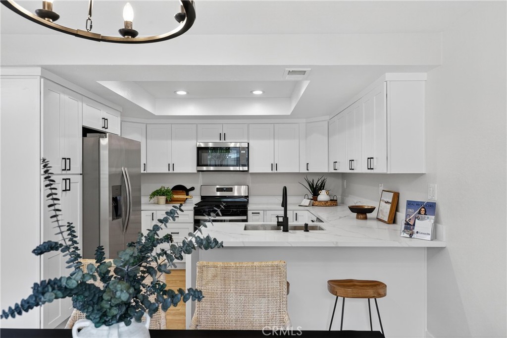 a kitchen with stainless steel appliances a sink a refrigerator a stove a microwave and island