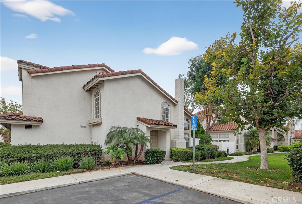 29 Carnation, Unit 64 Rancho Santa Margarita, CA 92688 - Photo 36 of 38 a view of a white house next to a yard with a tree