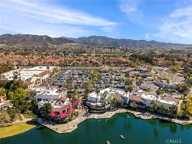 an aerial view of a city with lots of residential buildings ocean and mountain view in back