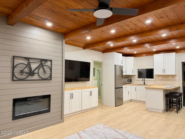 a living room with stainless steel appliances furniture a fireplace and a flat screen tv